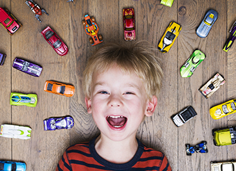 Laughing young boy surrounded by toy cars